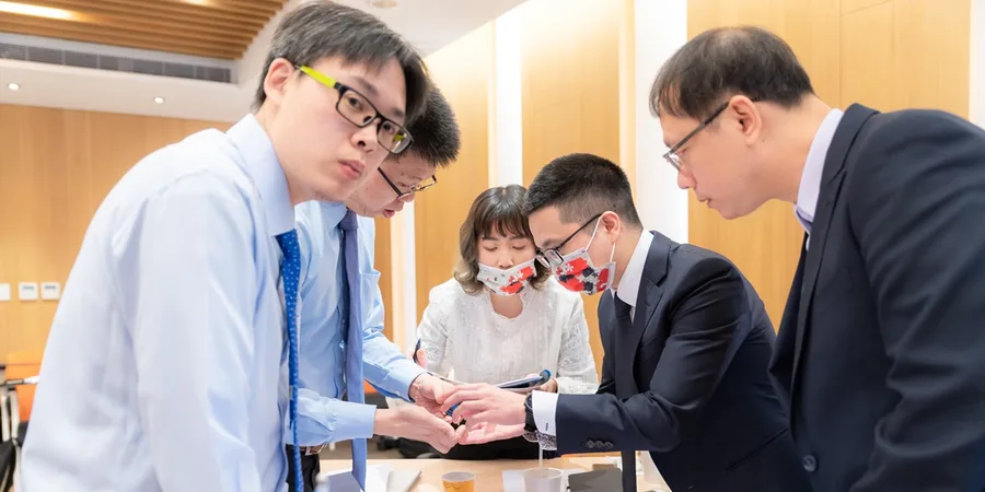 文章主視覺。上課中的小組討論，五位學員圍著桌子低頭研究手上的資料。