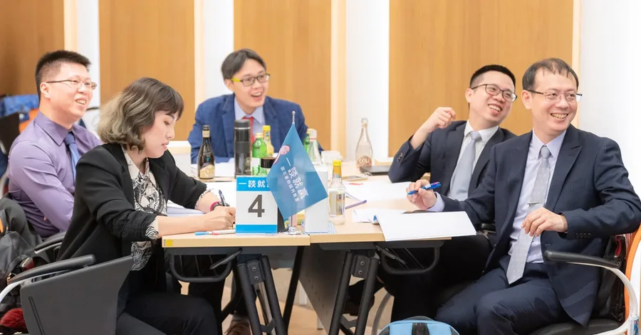 同組的五位學員坐在桌邊,桌上立著印有一談就贏字樣的小旗與第四組的桌牌,大家帶著笑意看向同一個方向。